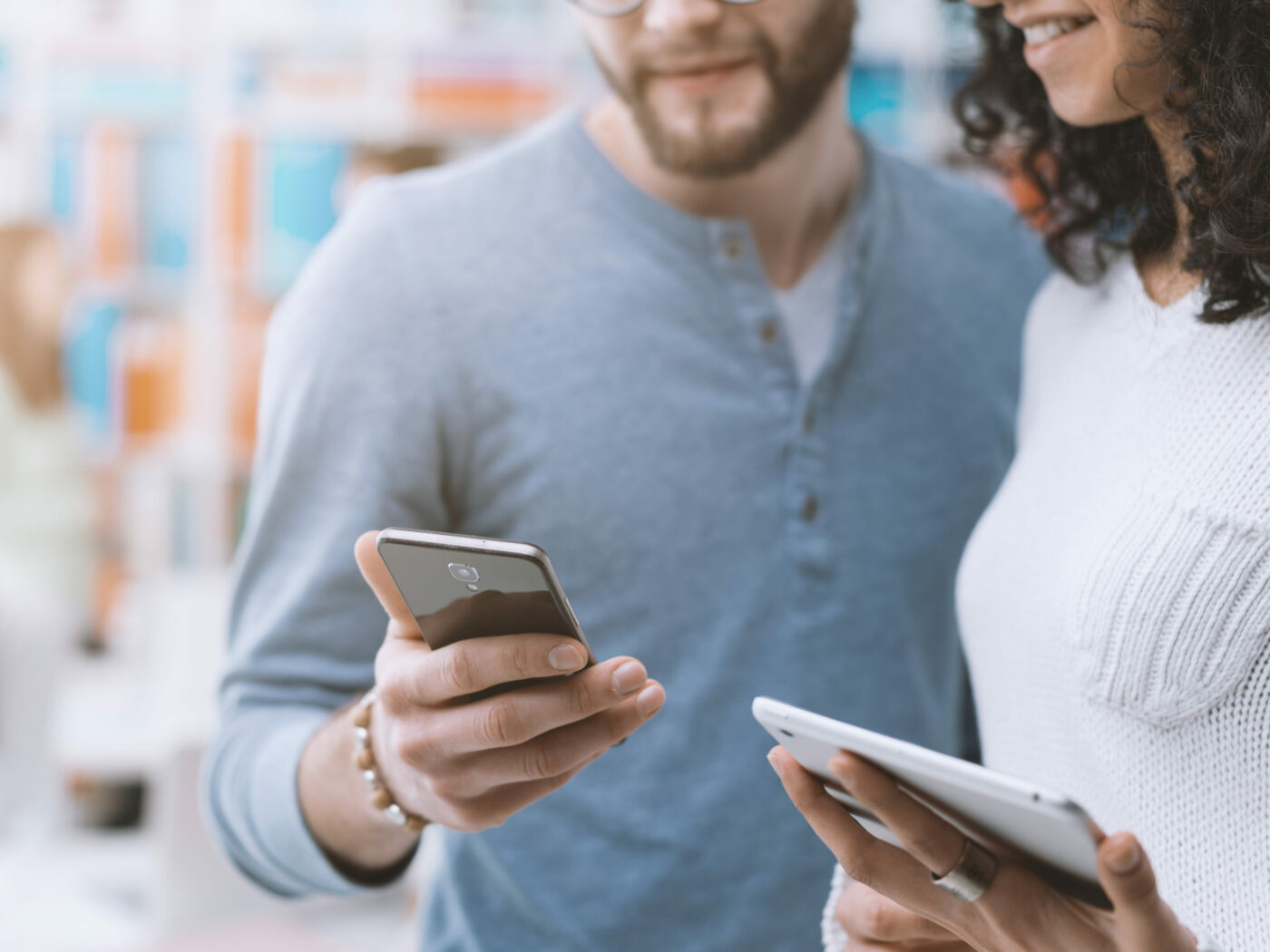 Amigos compartilhando conteúdo de mídia social em dispositivos móveis, segurando um smartphone e um tablet